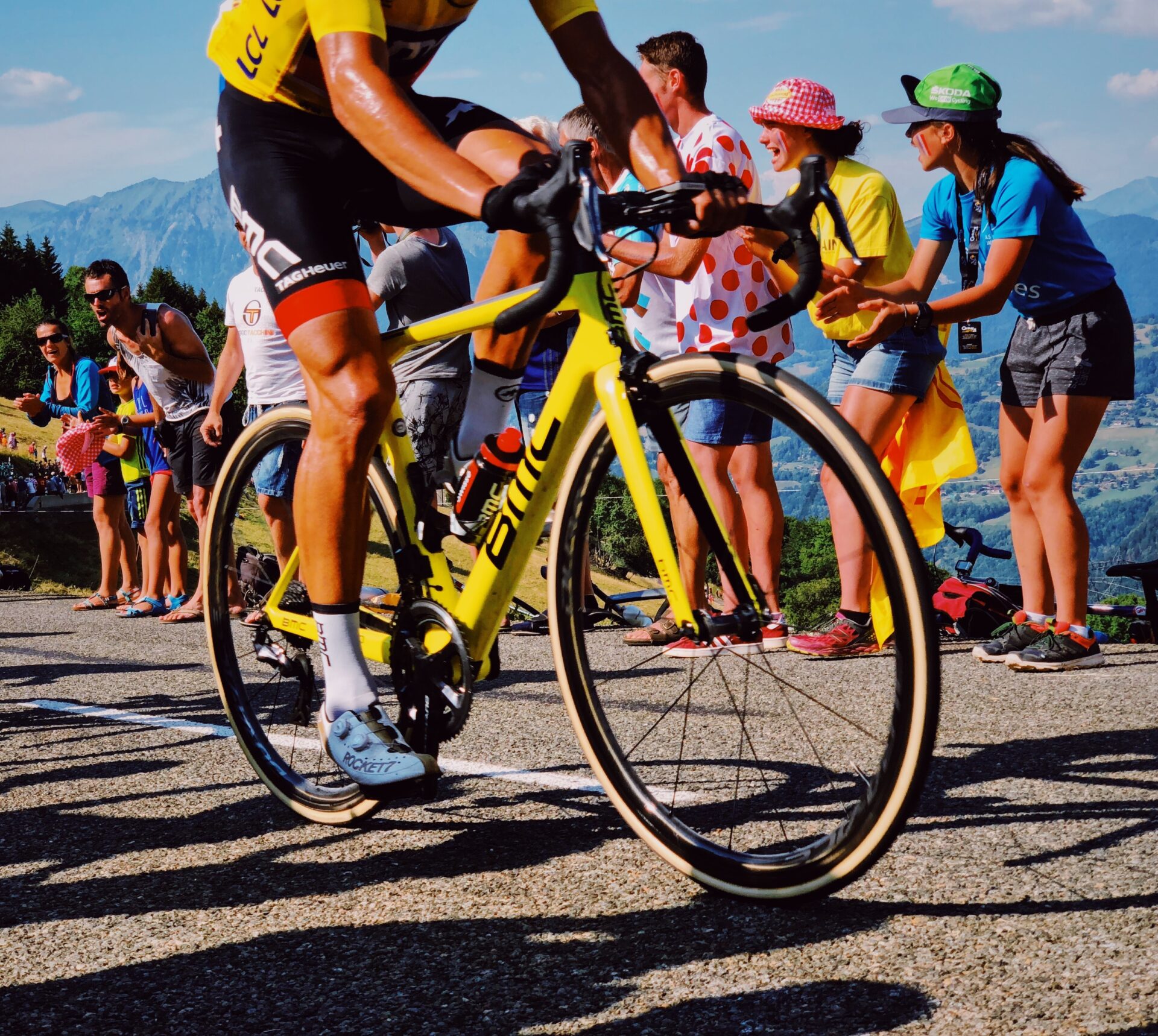 The yellow jersey rider of the Tour de France rides on a yellow BMC Road Bike, while pushing the pedals hard as a fast cyclist.